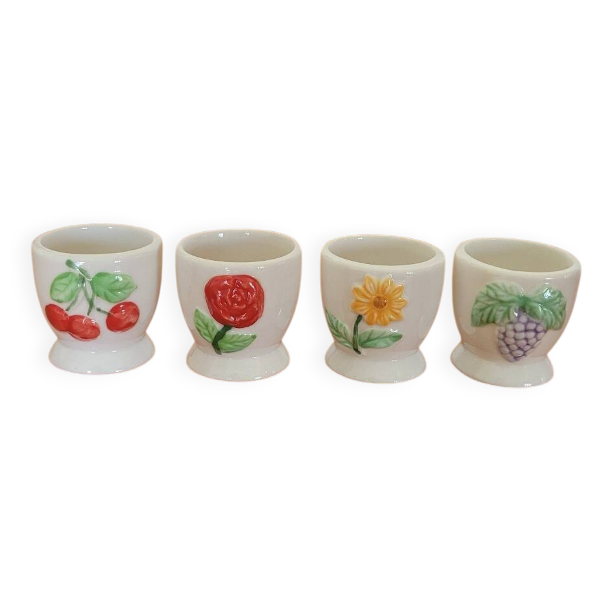 Set of four ceramic egg cups with a floral and fruit pattern.