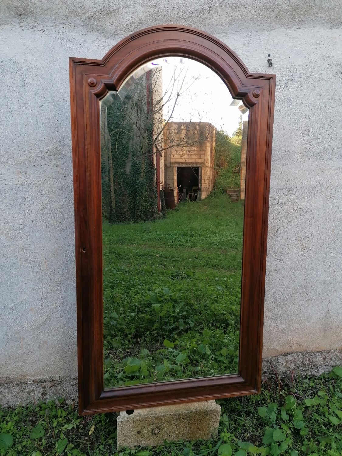 Old beveled solid wood mirror of a cabinet door.