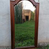Old beveled solid wood mirror of a cabinet door.