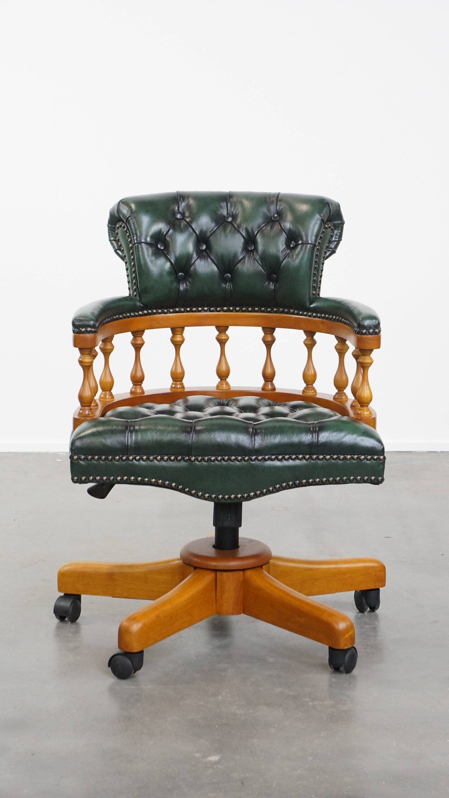 Classic green leather Chesterfield office chair on wheels.