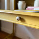 Desk table from the late 19th century, painted mustard, with turned stretcher.