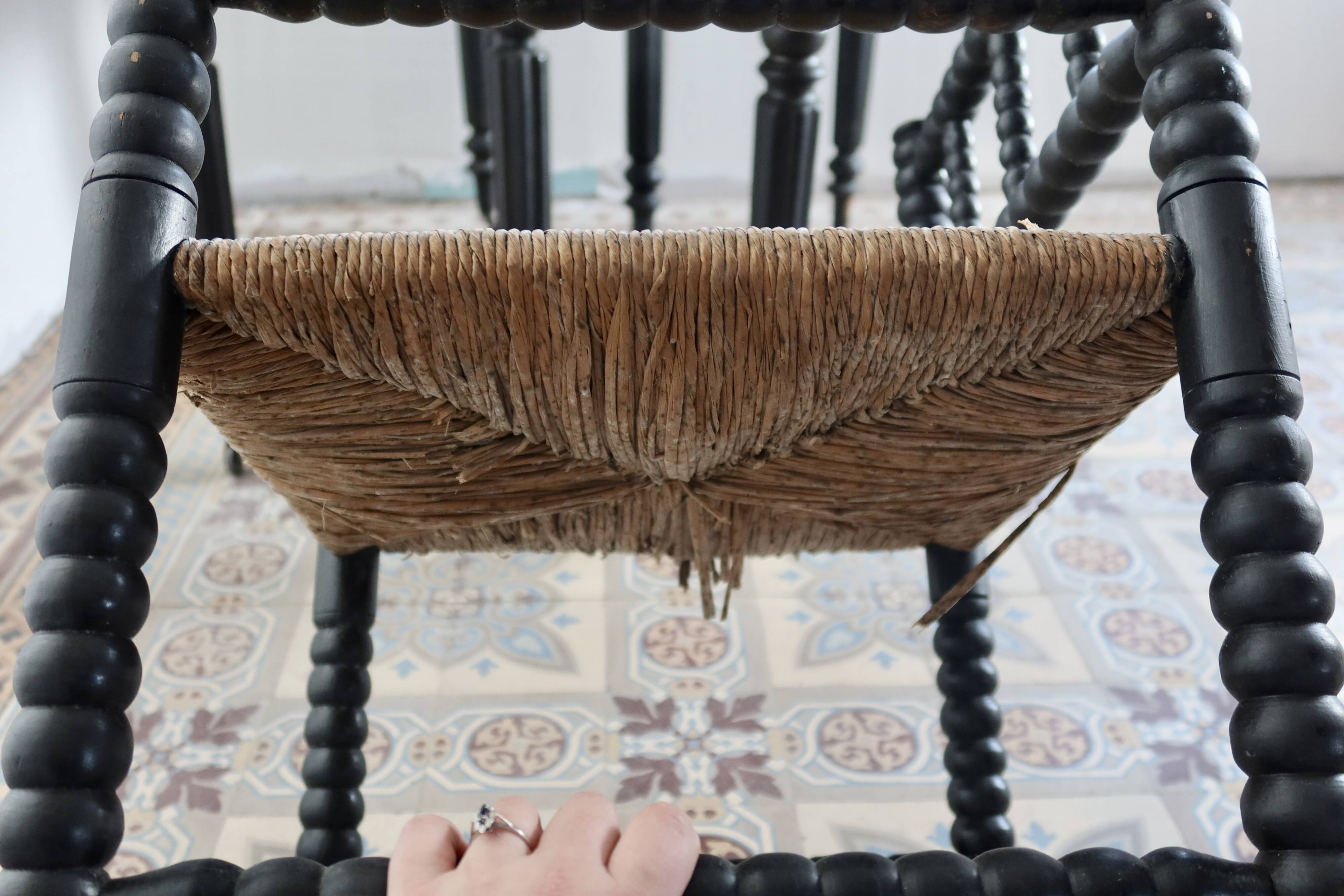 Antique black turned wood corner chair with a straw seat.