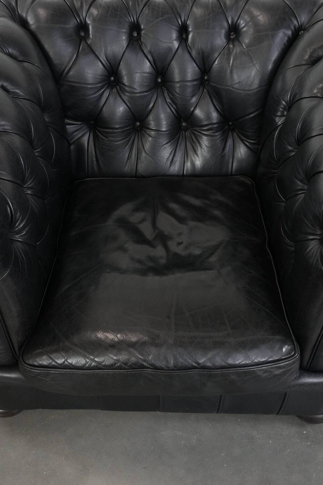 Set of a black cowhide leather Chesterfield armchair and matching ottoman