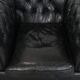 Set of a black cowhide leather Chesterfield armchair and matching ottoman