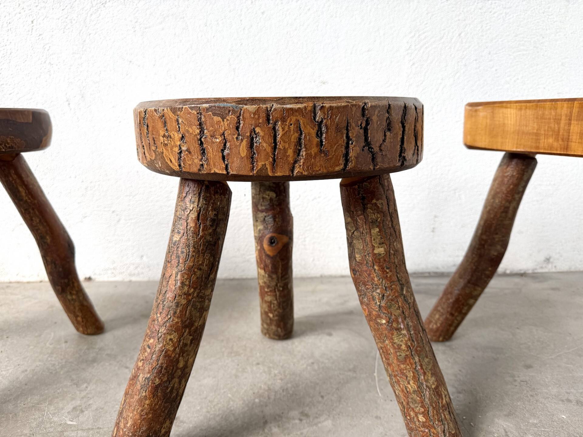 Set of three rustic solid wood tripod stools.