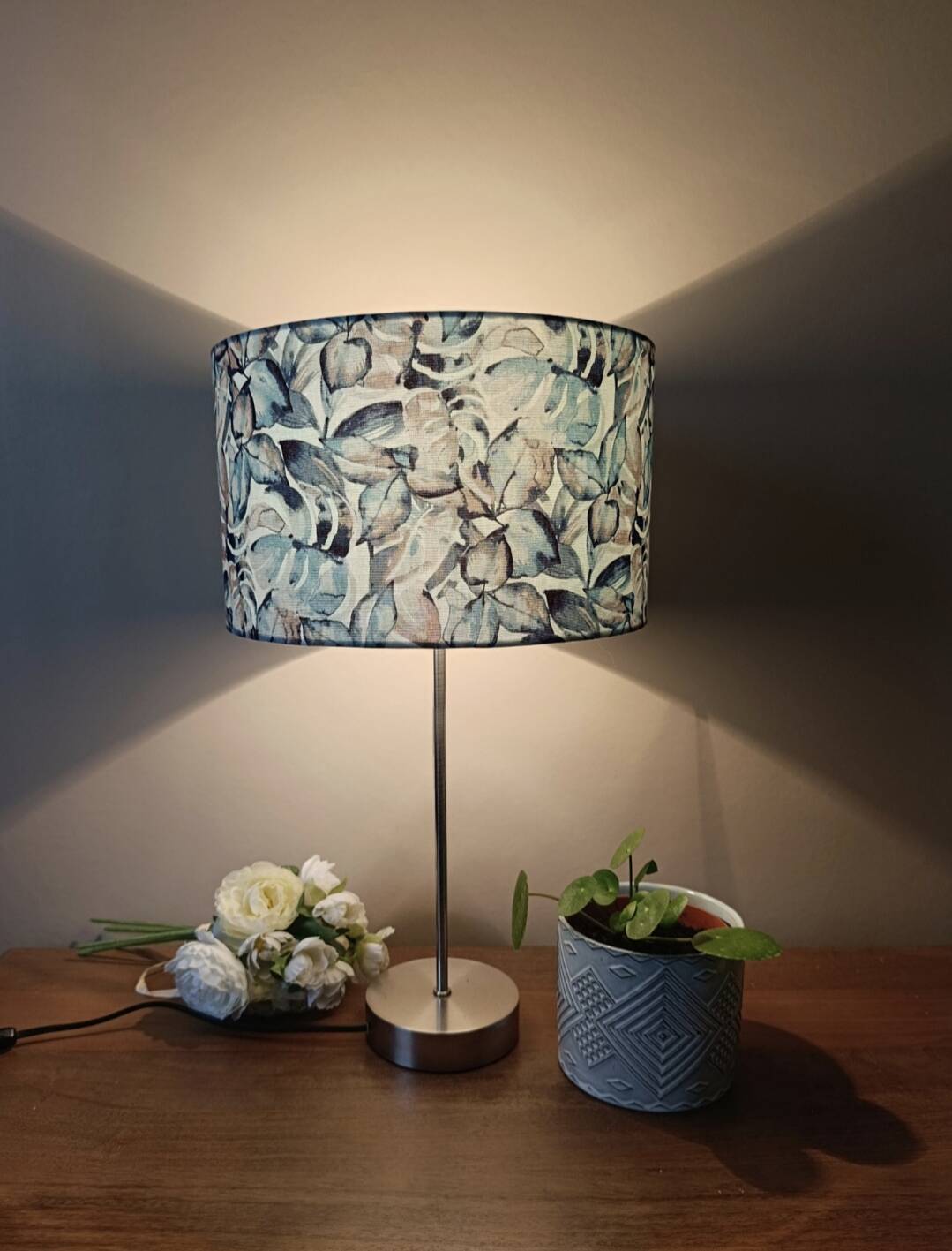 Table lamp with chrome stem, tropical plant shade.