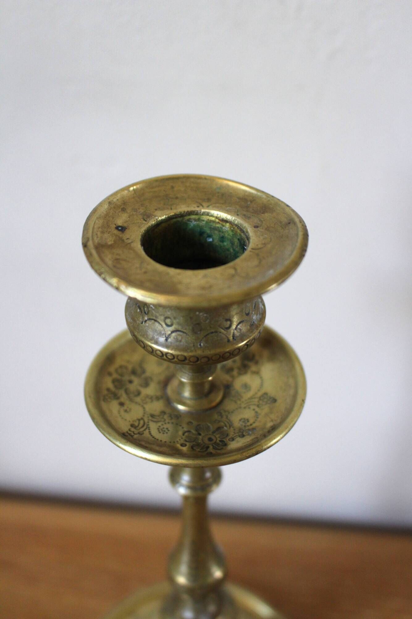 Brass candle holder with flowers and round shape.