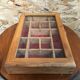 Old hanging display case with 15 wooden boxes, red background + vintage glass door
