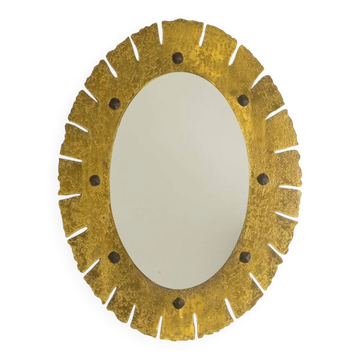 Elliptical mirror in hammered and gilded brass. 1950s-60s.