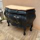 Curved commode painted in black and wood.