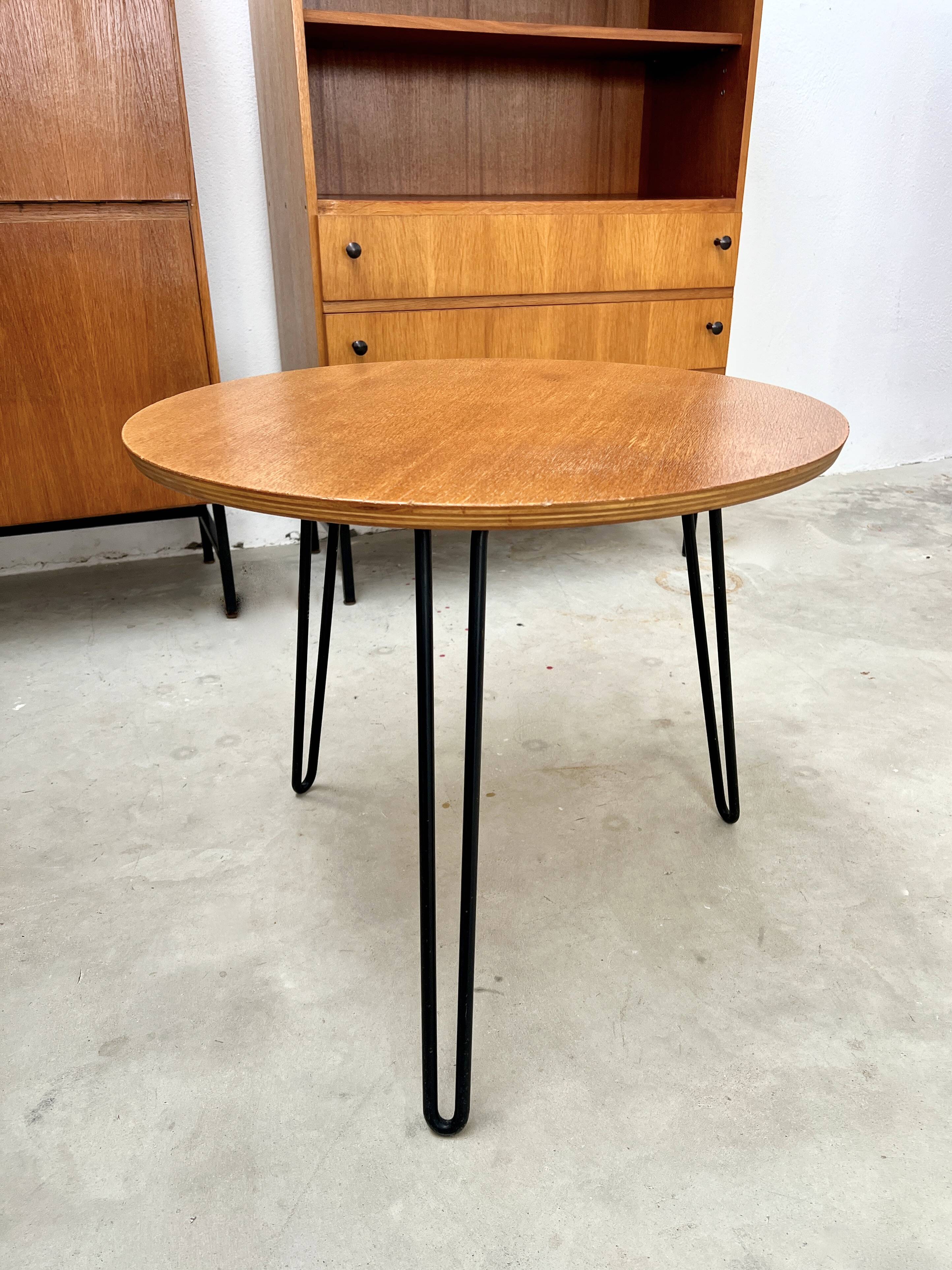 Round side table with black lacquered metal hairpin legs.