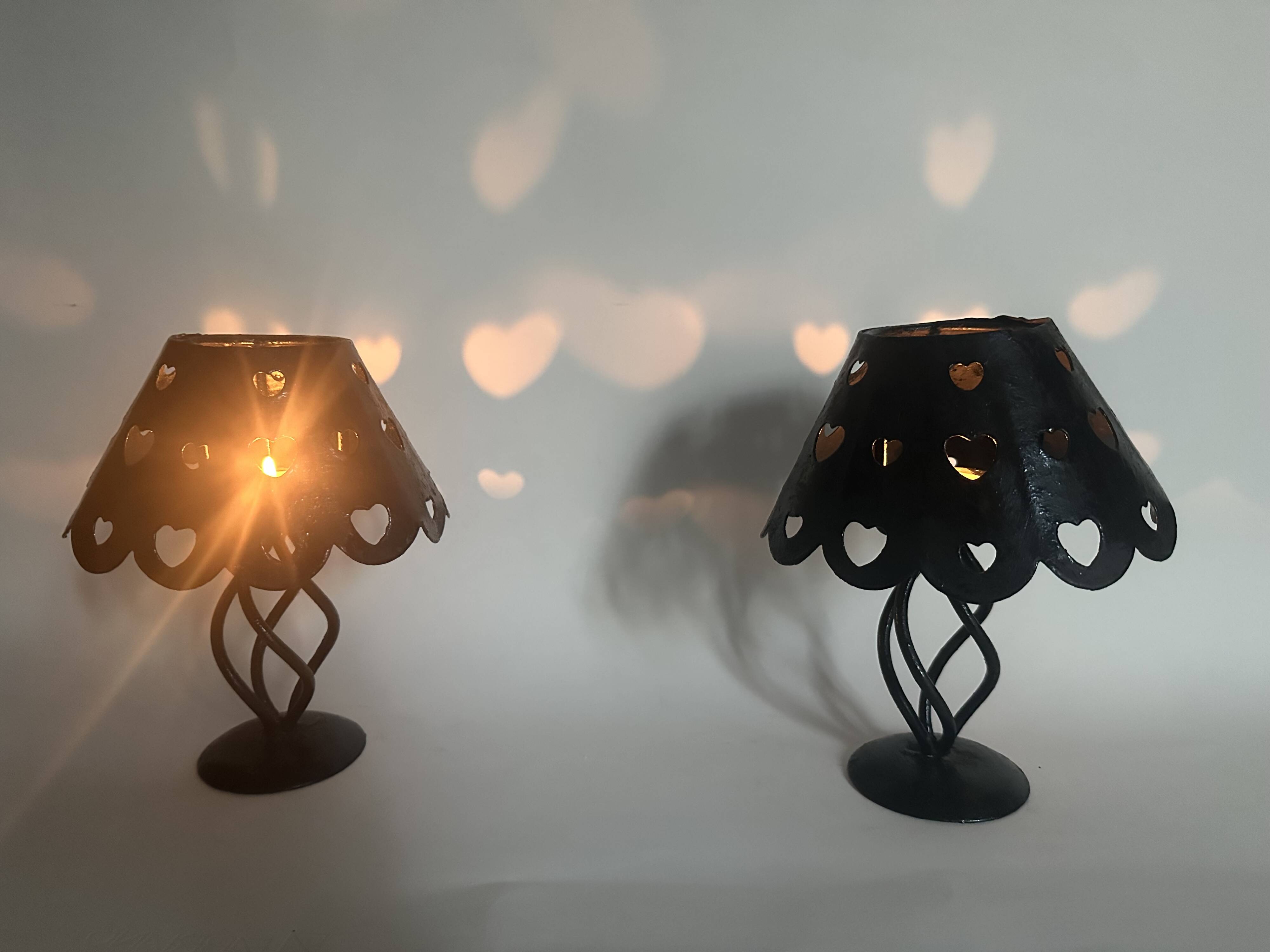 Pair of black wrought iron lanterns with heart patterns, romantic style.