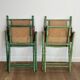 Paire de chaises safari pliantes façon faux-bambou patiné, dossiers et assises cannées et repose-bras en cuir