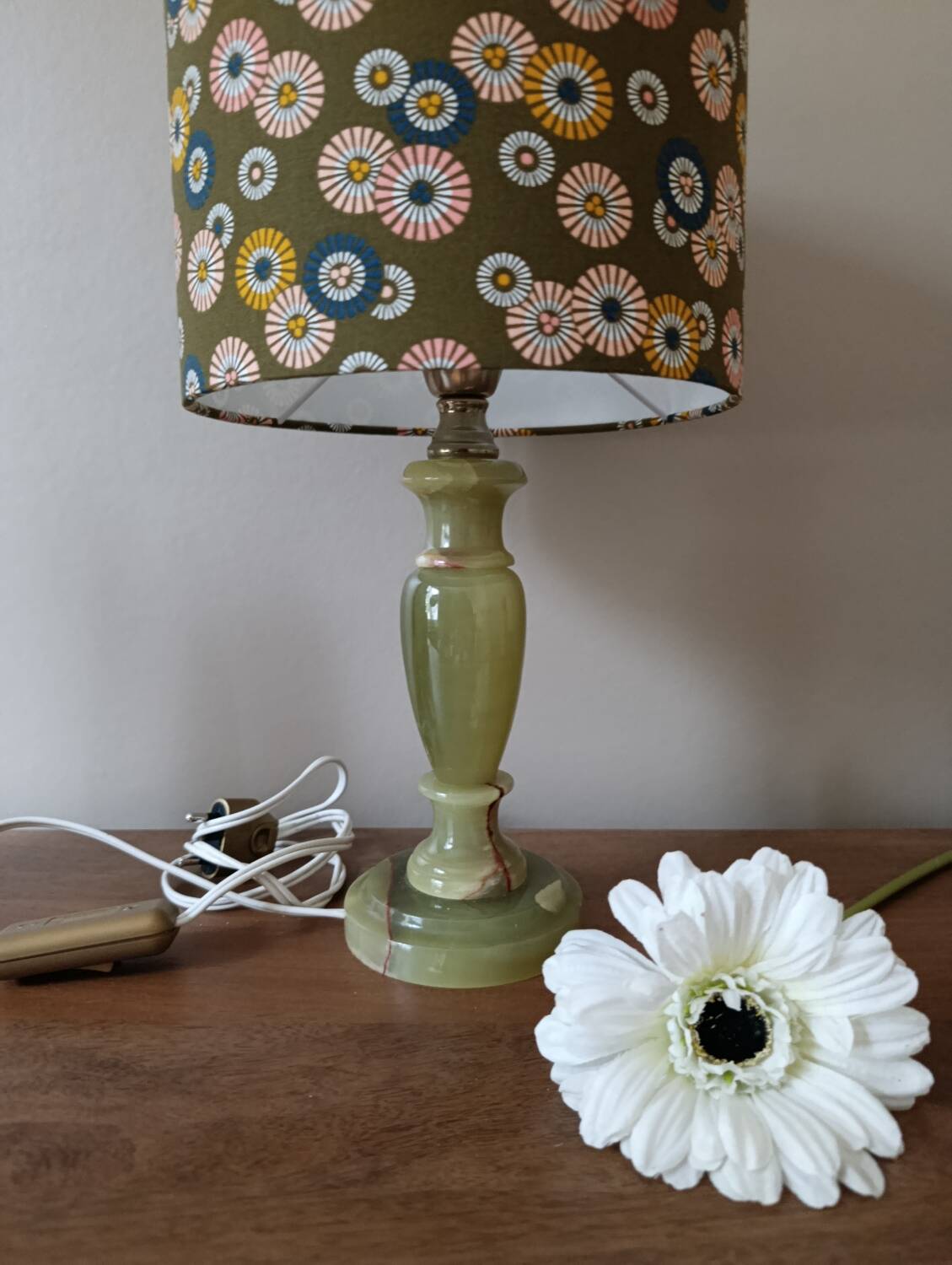 Table lamp with light green onyx base, fabric shade with a khaki background.