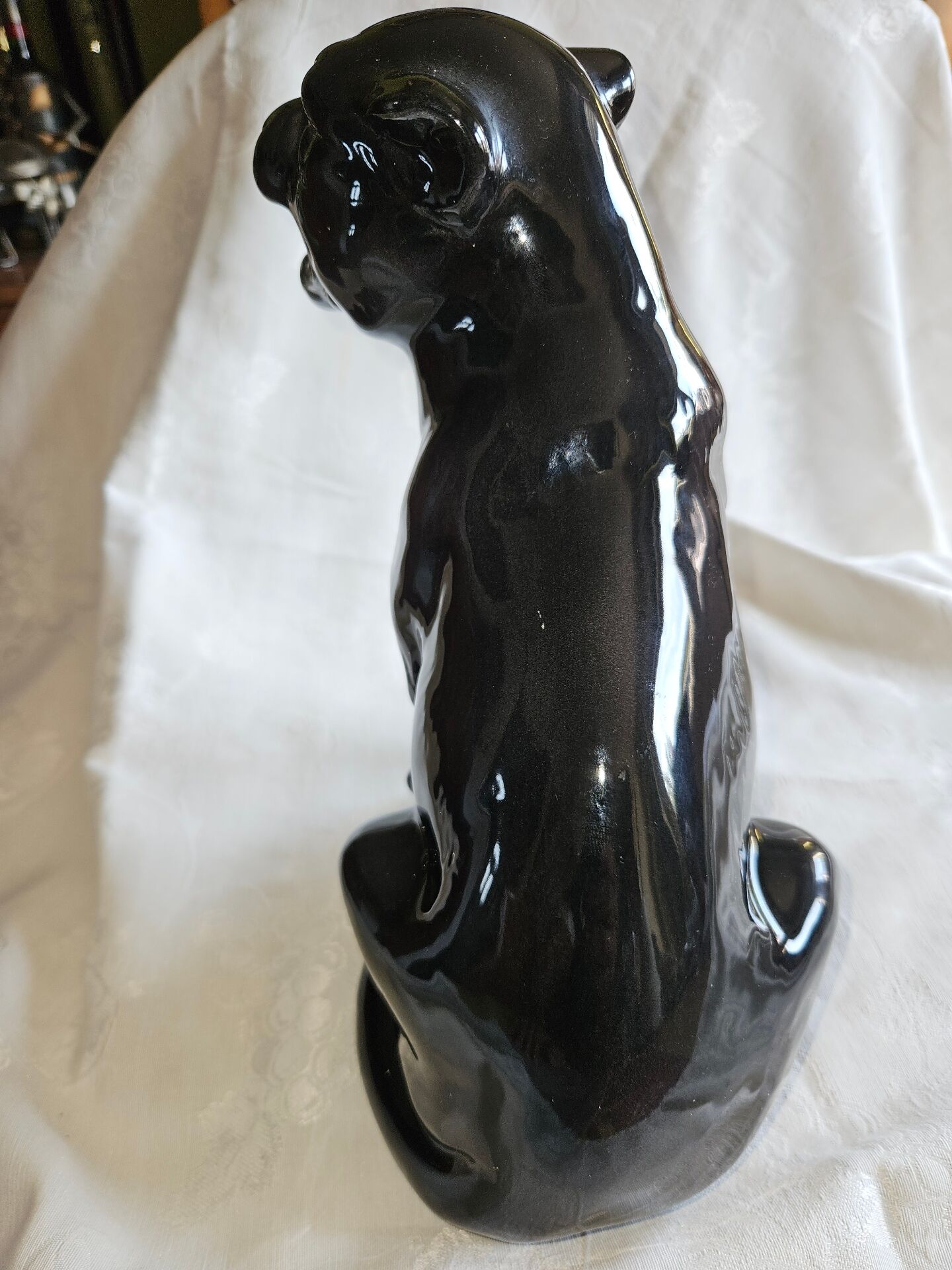Statue of a roaring panther/leopard sitting in black glazed ceramic.