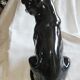 Statue of a roaring panther/leopard sitting in black glazed ceramic.