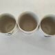 Set of three hand-painted porcelain cups with floral patterns.