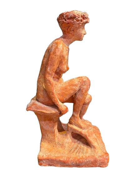 Painted plaster sculpture of a nude woman on a bench