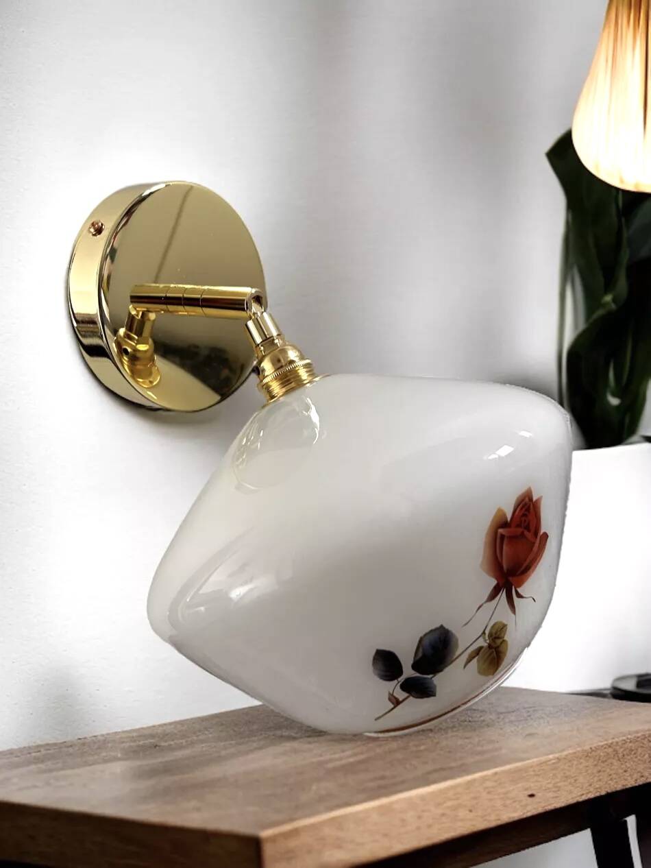Golden tilting wall light with flowered globe