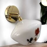 Golden tilting wall light with flowered globe