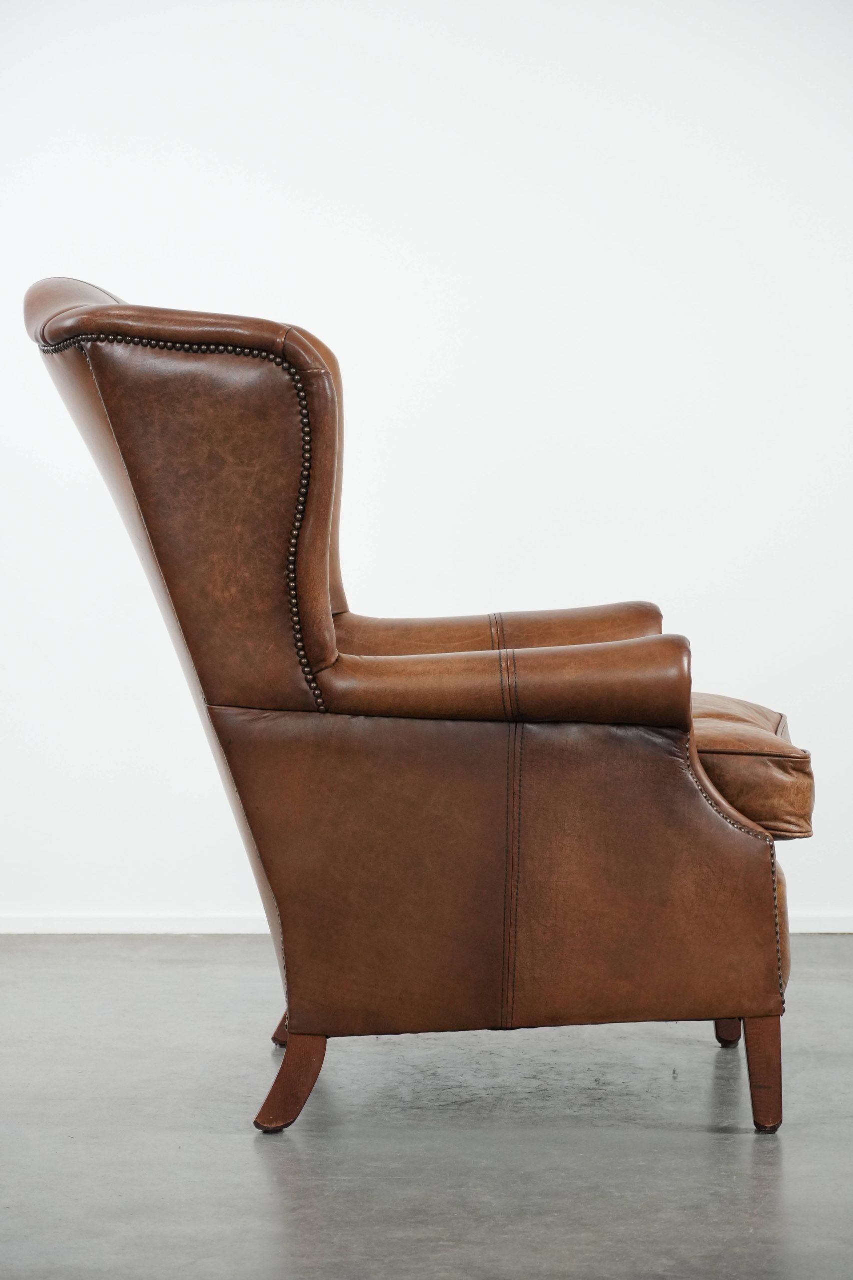 Cognac-coloured wingback armchair in English style made of cowhide leather