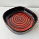 Large decorative ceramic catchall with red and black spiral pattern.