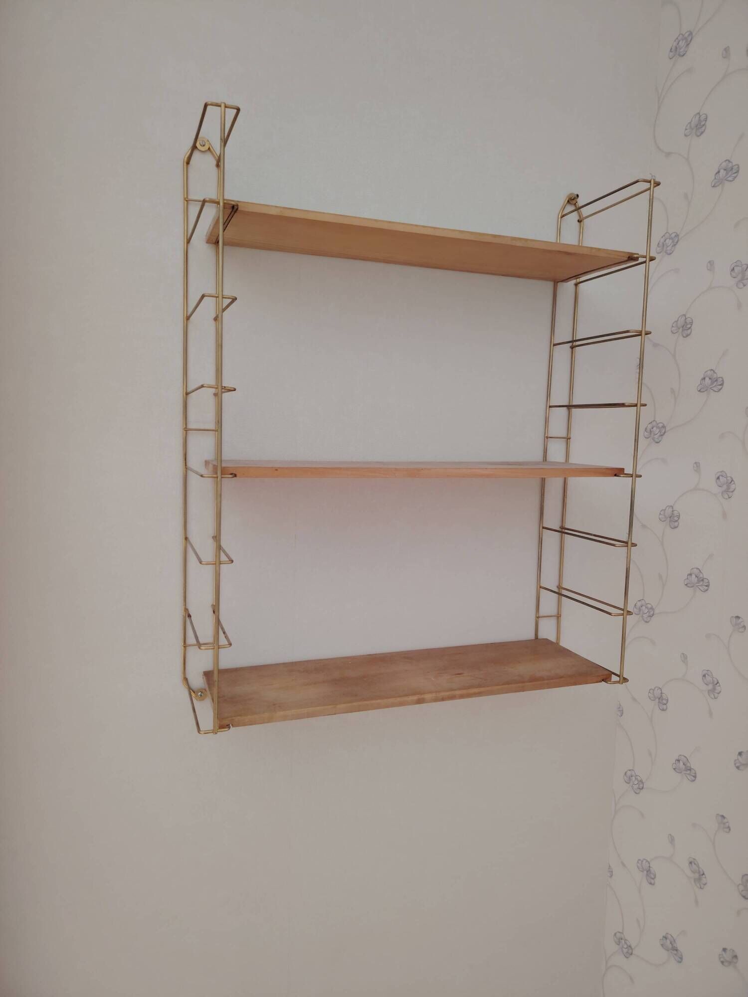 Vintage modular wall shelf in golden steel wire and wood from the 1950s.
