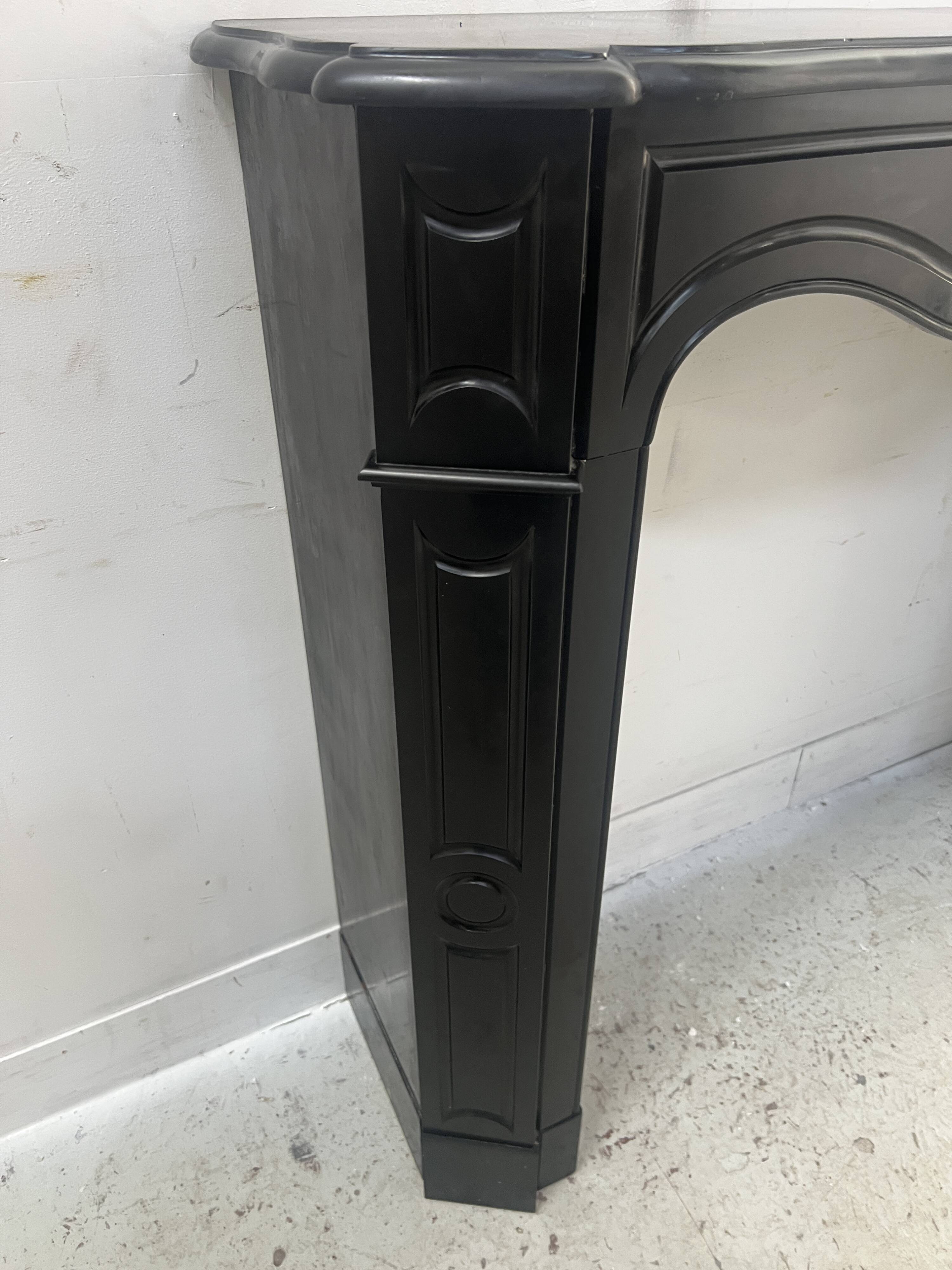 Cheminée de style Louis XV modèle Pompadour en marbre noir moucheté, XXe siècle