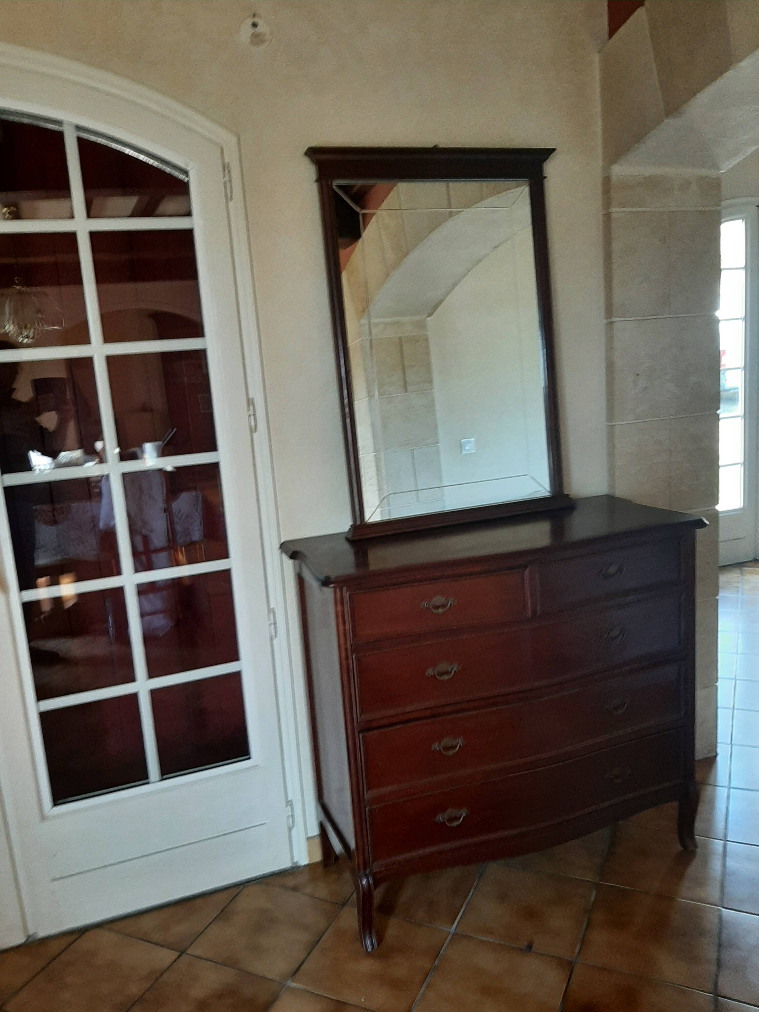Style set: bevelled mirror and curved wooden chest of drawers.