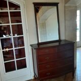 Style set: bevelled mirror and curved wooden chest of drawers.