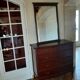 Style set: bevelled mirror and curved wooden chest of drawers.