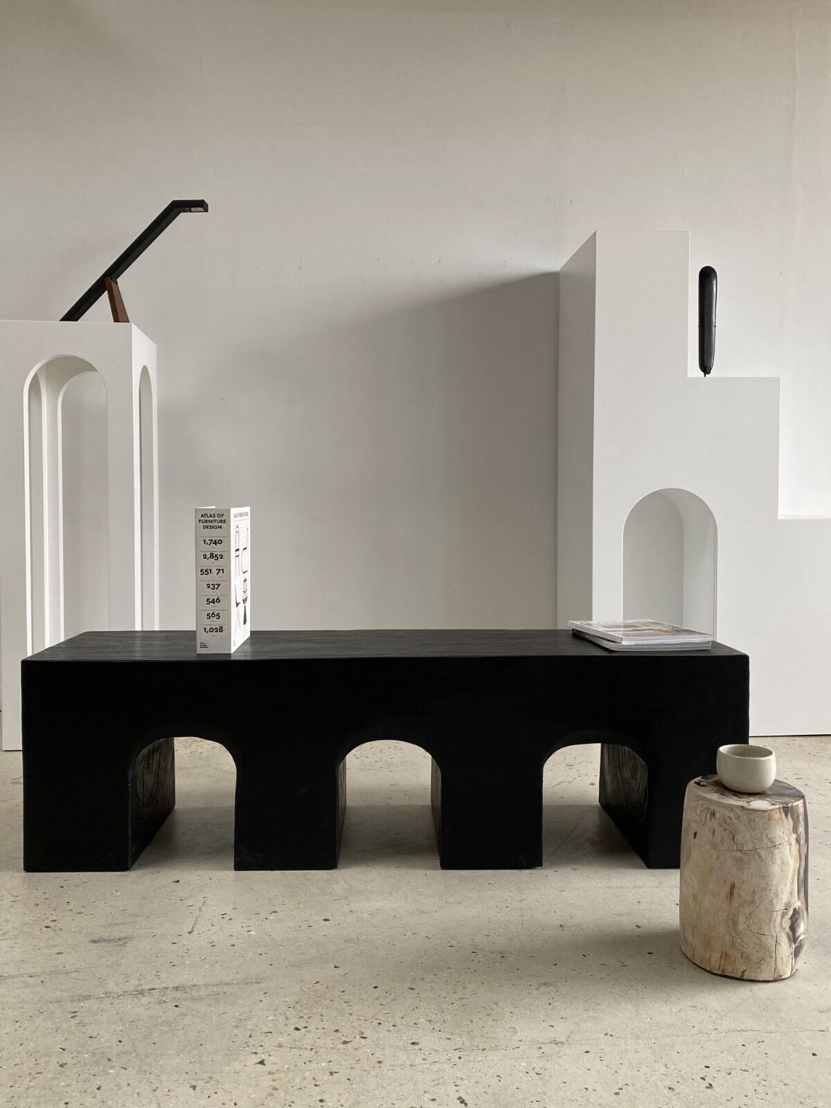 Black solid monoxyl wood bench carved into 3 arches