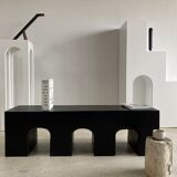 Black solid monoxyl wood bench carved into 3 arches