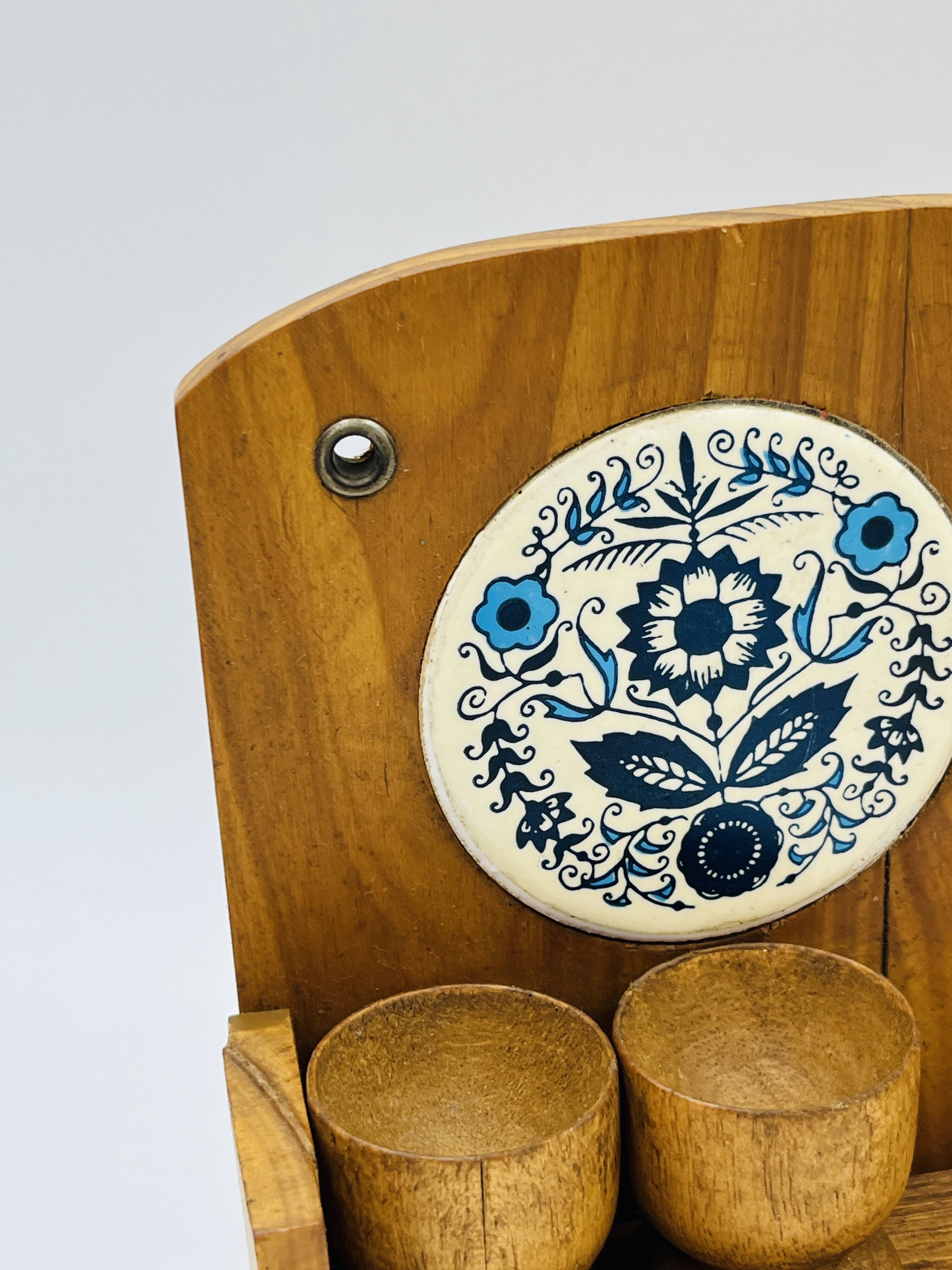 Wall-mounted egg cup holder and wooden utensil holder.