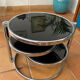 Coffee table with pivoting metal and black glass elements.