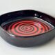 Large decorative ceramic catchall with red and black spiral pattern.