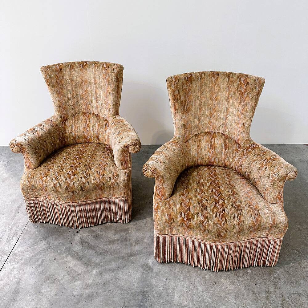 Pair of sculptural Hollywood Regency lounge chairs with original fringed upholstery