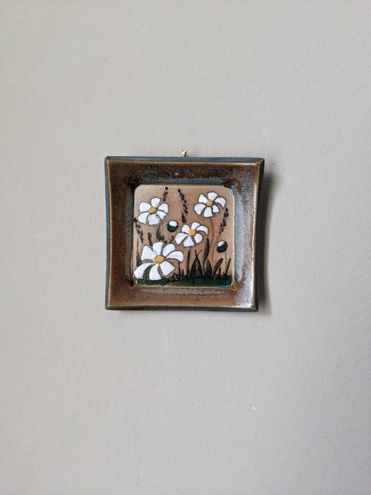 Handcrafted ceramic wall hanging with floral daisy decoration