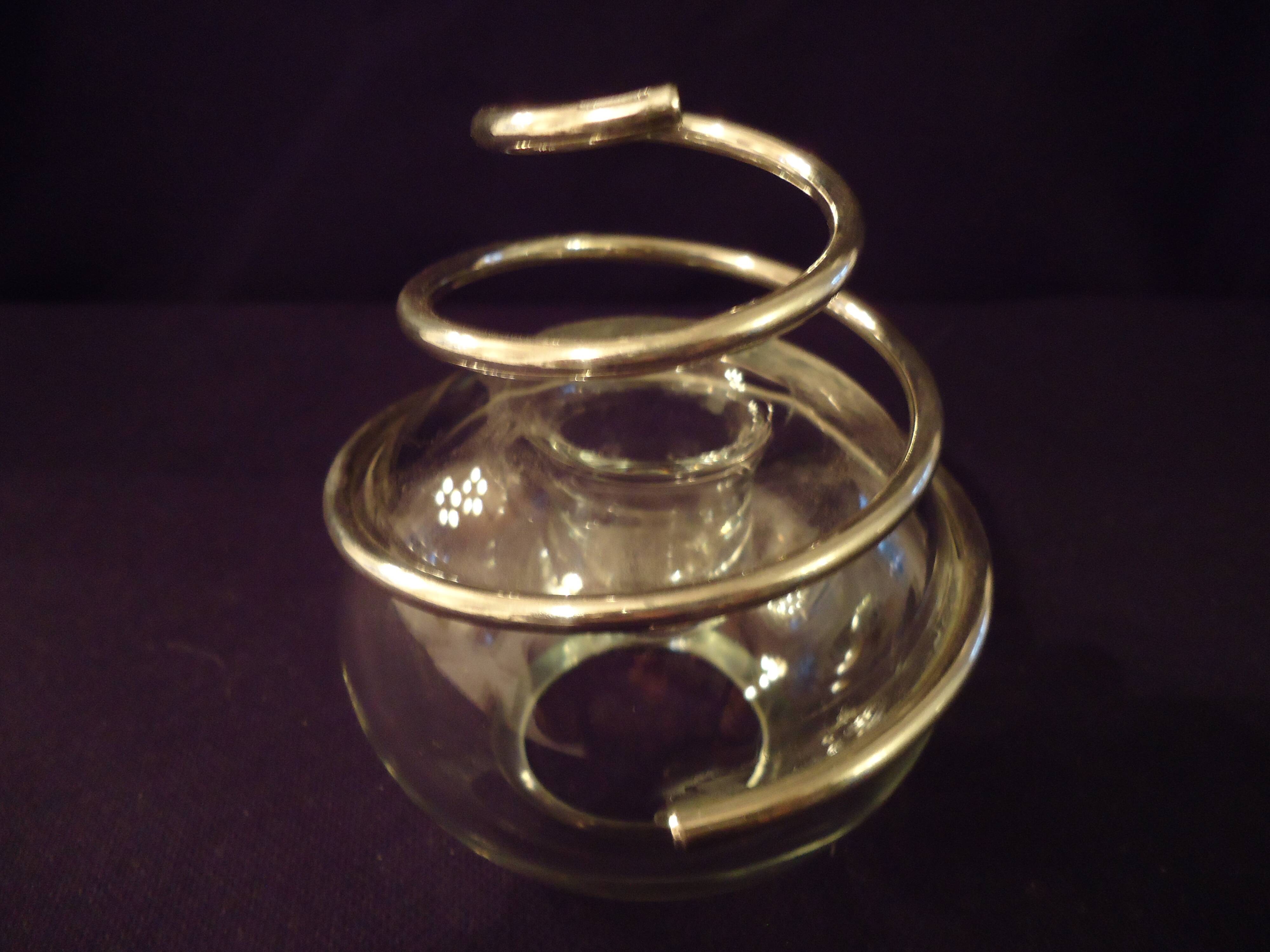 Round glass candle holder with silver-plated metal spiral.
