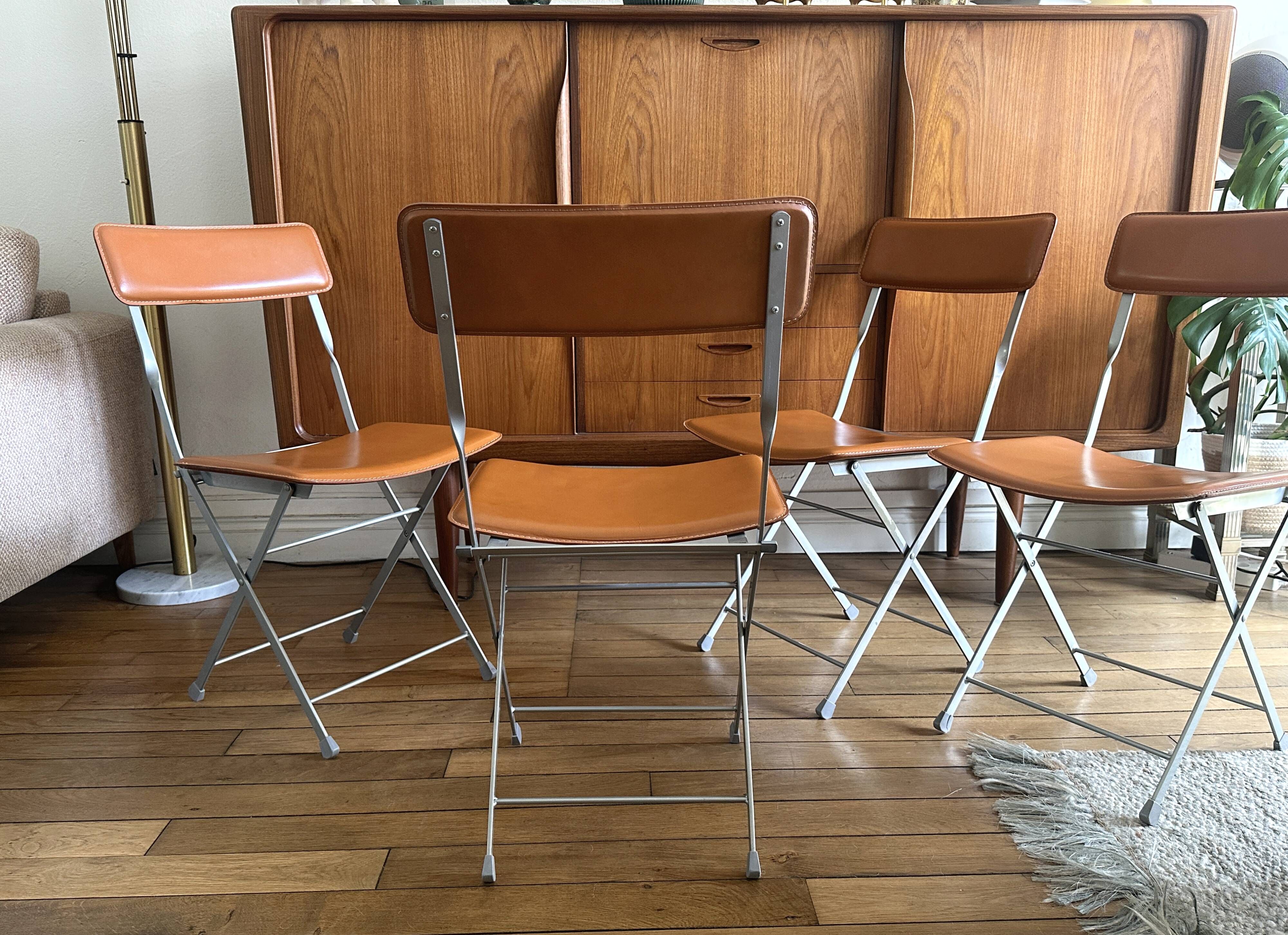 4 folding Sintesi chairs for DWR Lina in metal and vintage camel leather.