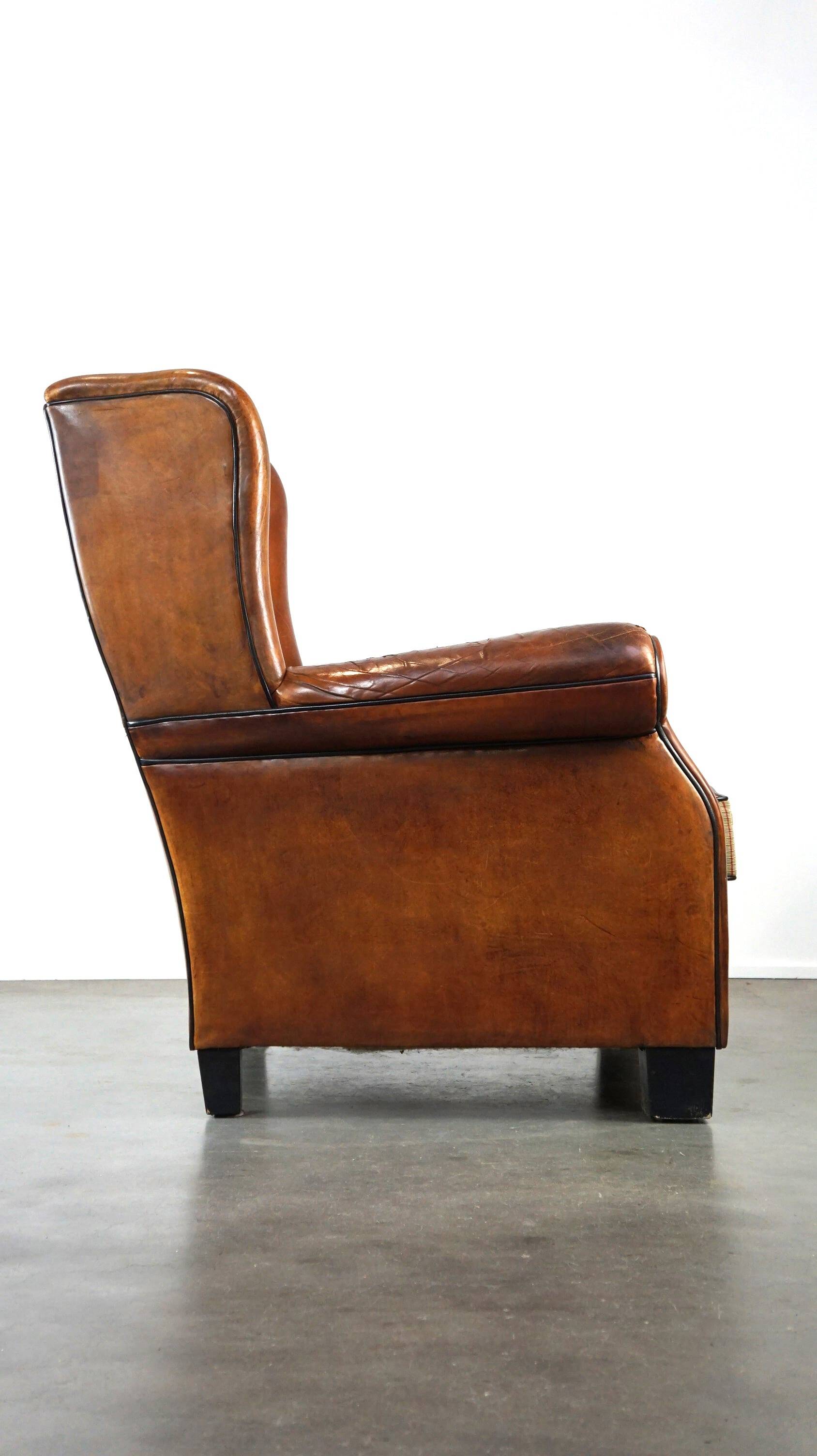 Very large worn sheepskin wing chair with a checked seat cushion