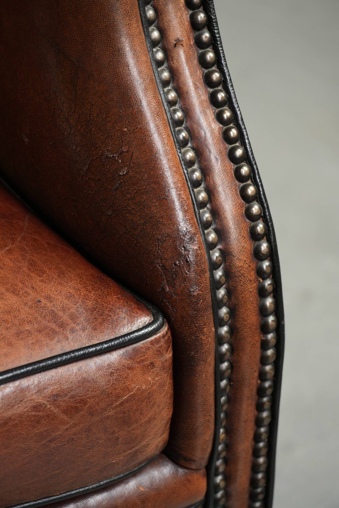 Sheepskin wingback armchair finished with black piping and a correct seat