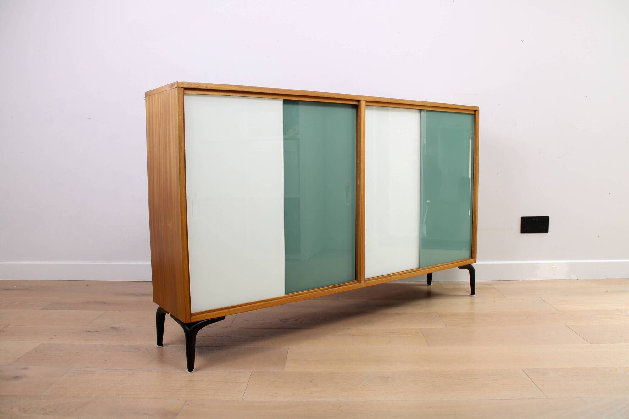 A vintage mid-century bookshelf/sideboard with green and white sliding door