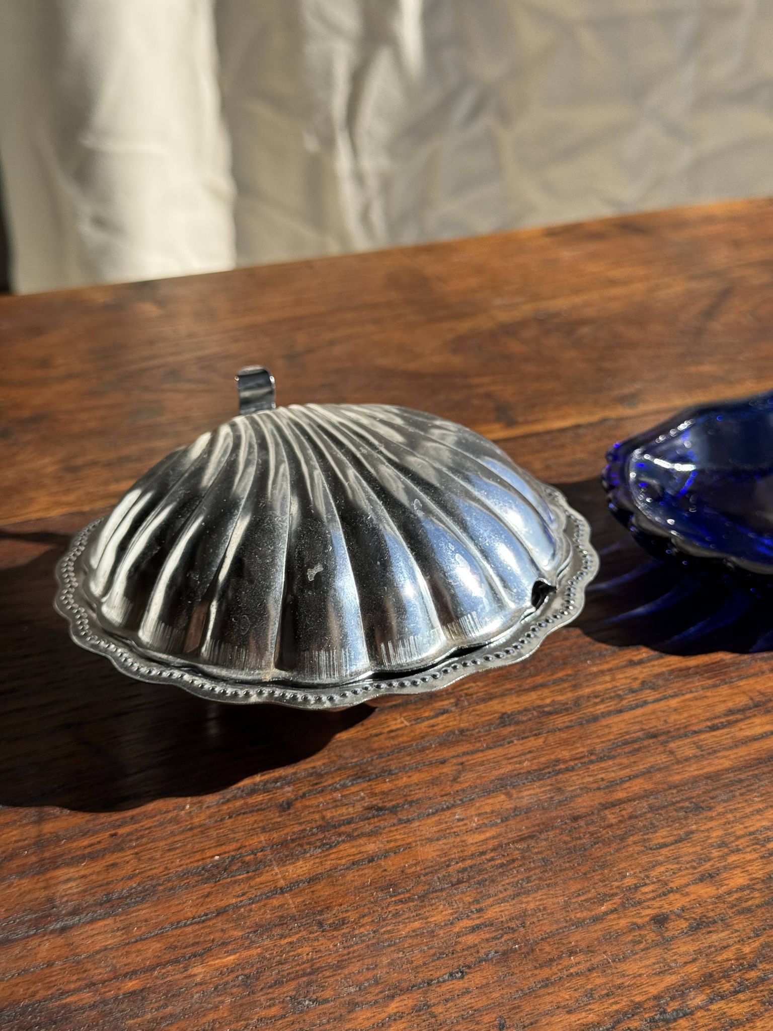 Vintage silver-plated shell butter dish with blue bowl.