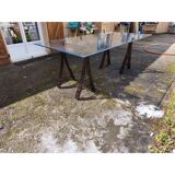 Vintage table with a glass top and smoked plastic trestle legs.