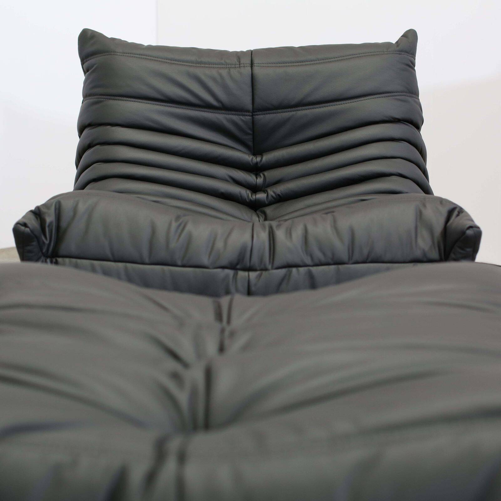 Togo armchair and footrest in black leather by Ligne Roset, designed by Michel Ducaroy.