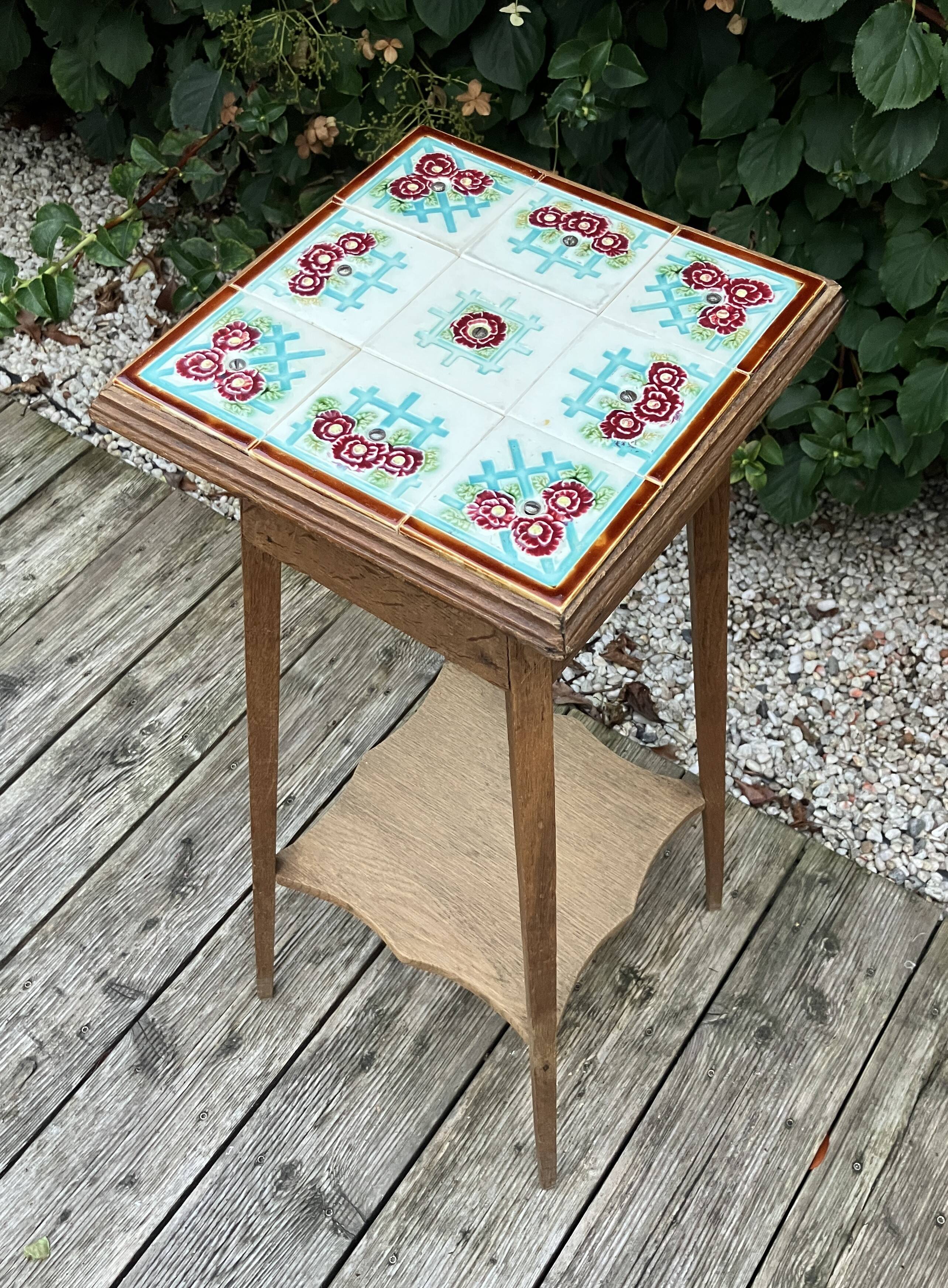 Antique wooden plant stand with ceramic tiles.