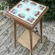 Antique wooden plant stand with ceramic tiles.