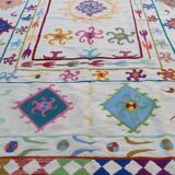 White suzani kilim rug with multi-colored embroidered patterns