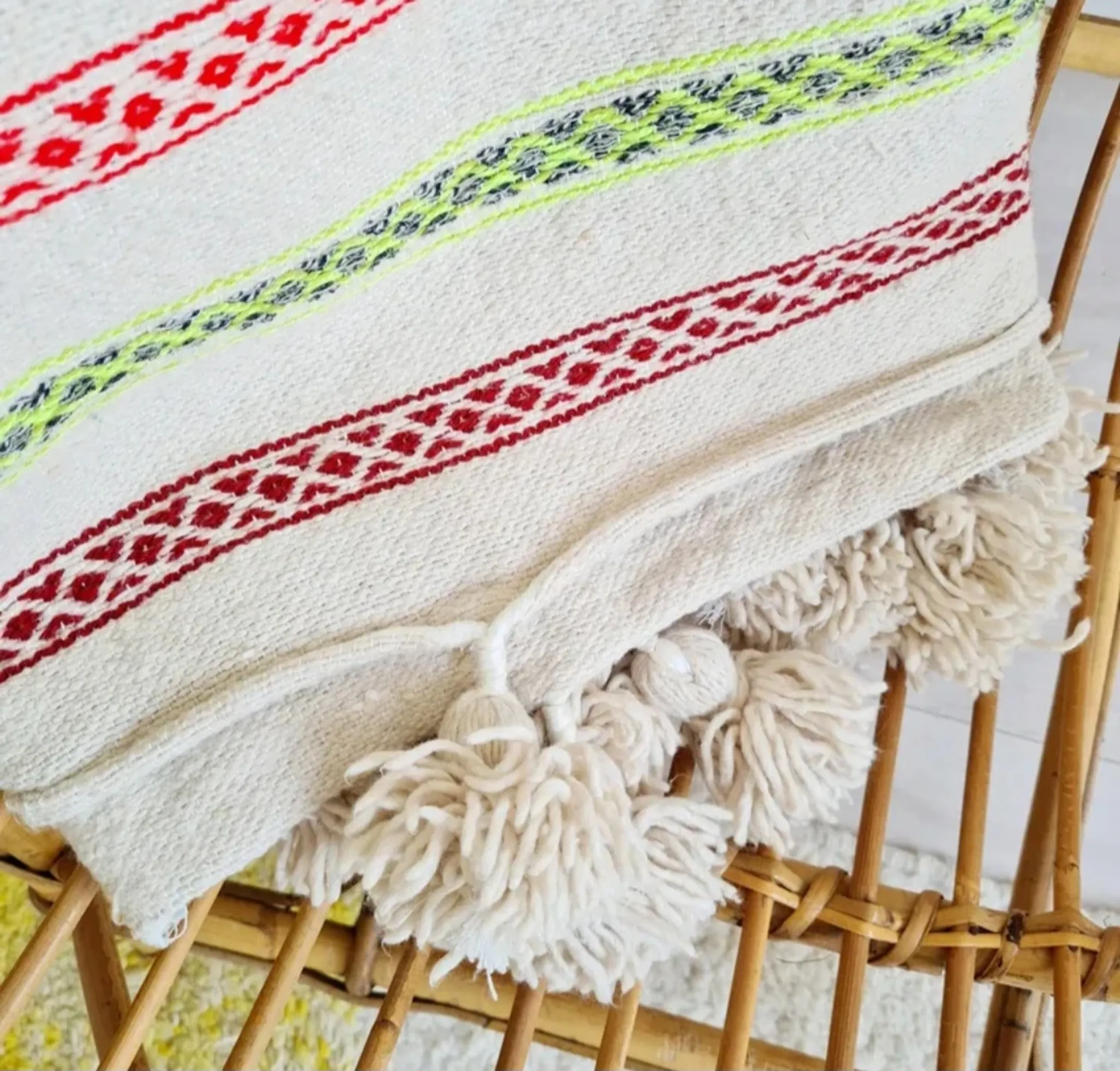 Moroccan plaid made of handwoven wool, decorated with stripes and pom-poms.